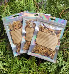 three bags of dried herbs sitting on top of a green tree covered in holographics