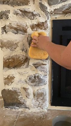 a person wiping up a stone wall with a sponge