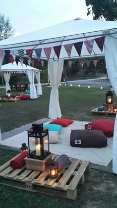 an image of a tent set up in the grass with lanterns and pillows on it