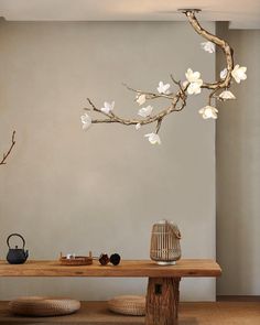 a wooden table topped with a vase filled with white flowers next to a tree branch