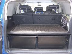 the back end of a blue van with two large storage bins in it's trunk