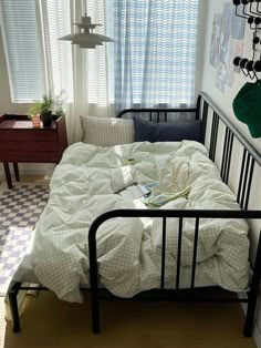 an unmade bed in a small room with checkered flooring