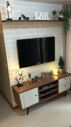 a living room with a large flat screen tv on the wall and plants in front of it