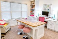 a kitchen island with two stools in front of it and a tv on the wall