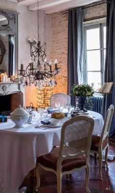 a dining room with a table, chairs and a chandelier hanging from the ceiling