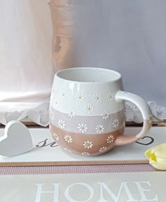 a coffee mug sitting on top of a table next to a flower pot and spoon