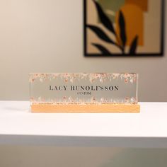 an acrylic business card sitting on top of a white table next to a painting