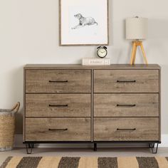 a room with a dresser, lamp and pictures on the wall