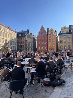 a group of people sitting around tables in front of buildings