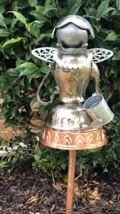 an old fashioned stove sitting on top of a wooden stand in front of some bushes