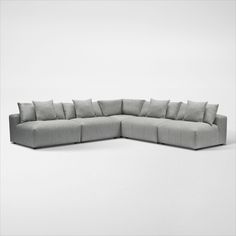 a large sectional couch with many pillows on it's back end and sides, facing the camera