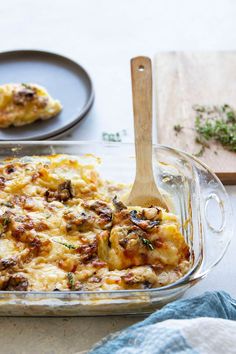 a casserole dish with meat and vegetables in it next to a wooden spoon