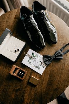 a pair of black shoes sitting on top of a wooden table next to a card