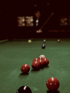 several red and black pool balls on a green billiard's table in a dark room