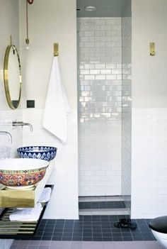 a bathroom with black and white tile flooring, gold fixtures and a glass enclosed shower stall