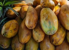 a pile of mangoes sitting on top of each other next to a pineapple