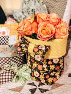 a vase filled with orange roses sitting on top of a quilt