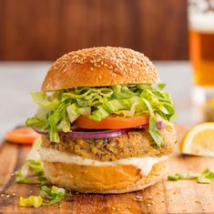 a burger with lettuce, tomato and onion on a wooden cutting board