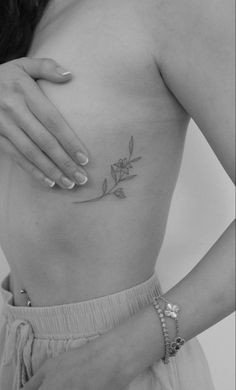 a woman's stomach with a rose tattoo on her left side, showing the breast area