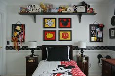 a bedroom with mickey mouse pictures on the wall and other items in the shelves above it