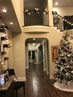 a decorated christmas tree in the middle of a living room with stairs leading up to it