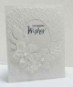 a white wedding card with flowers and pearls on the front, which reads wishing wishes