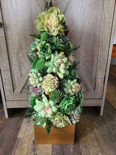 a christmas tree made out of succulents and greenery on a wooden stand