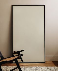 a chair sitting in front of a white poster on the wall next to a rug