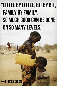 two children are standing in the dirt and one is holding a yellow bucket with water on it