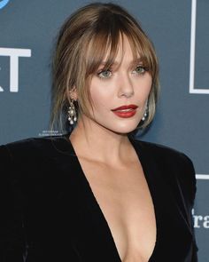 a close up of a person wearing a black dress with red lipstick on her lips