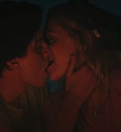 two people kissing in front of a lit candle