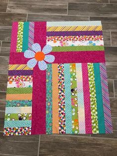 a patchwork quilt with a flower on the center and many different colored strips around it