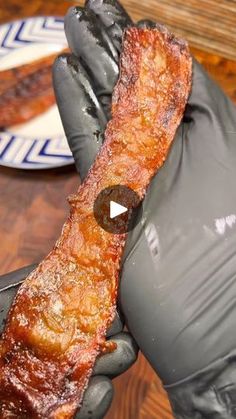 a person wearing gloves holding up a piece of meat