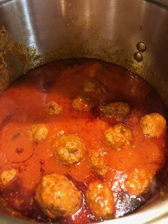 some meatballs are cooking in a pot with red sauce on the bottom and sides