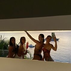 three women taking a selfie in front of the ocean with their cell phones up