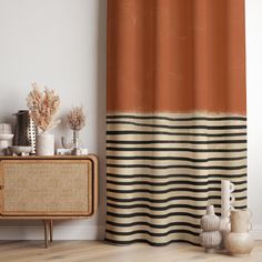 an orange and black striped shower curtain next to a cabinet with vases on it