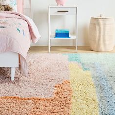 a child's bedroom with pink, blue and yellow rugs on the floor