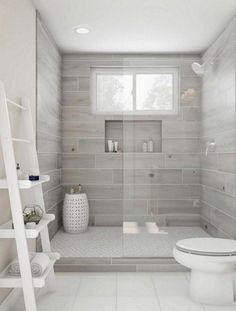 a white toilet sitting in a bathroom next to a shower and ladder with towels on it