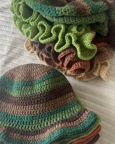 there are many crocheted hats on top of each other, one is green and the other is brown