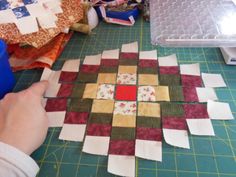 someone is working on some quilts that are laying on the table next to them