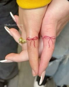 two people with wedding rings and bows on their fingers are holding each other's hands