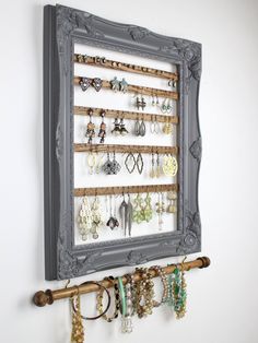 a wall mounted jewelry rack with several pairs of earrings hanging from it's sides