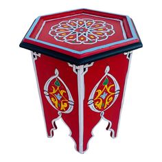 a red and white table with an ornate design on the top, sitting in front of a white background