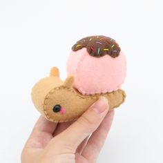 a hand holding a small stuffed animal with an ice cream cone on top