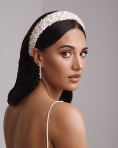 a woman wearing a white headband with pearls on it's side and her hair pulled back