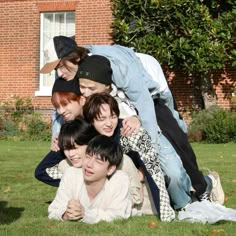 a group of young people laying on top of each other in front of a brick building