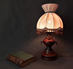 a lamp that is sitting on top of a table next to an old book and a light