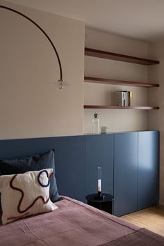 a bed sitting in a bedroom next to a wall mounted book shelf with books on it