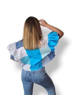 a woman in jeans and a top with blue squares on it is looking back at the camera