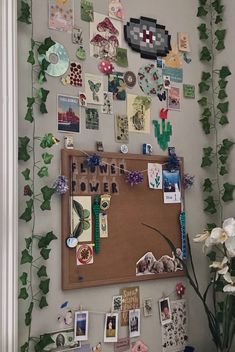 a bulletin board covered in pictures and magnets on a wall with ivy growing over it